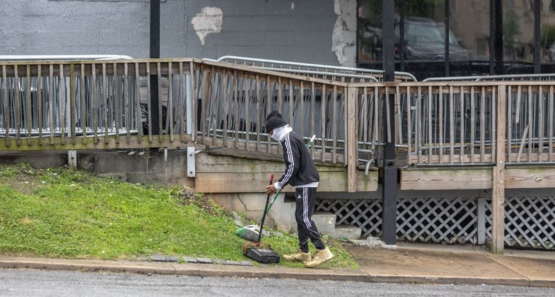 A man picks up trash Monday outside a Buckhead nightclub where two people were shot and killed early Sunday. 