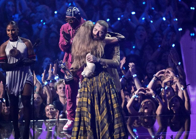 Taylor Swift, center, and Post Malone embrace as they accept the award for best collaboration for "Fortnight" during the MTV Video Music Awards on Wednesday, Sept. 11, 2024, at UBS Arena in Elmont, N.Y. Jordan Chiles, far left, and Flava Flav look on.(Photo by Charles Sykes/Invision/AP)