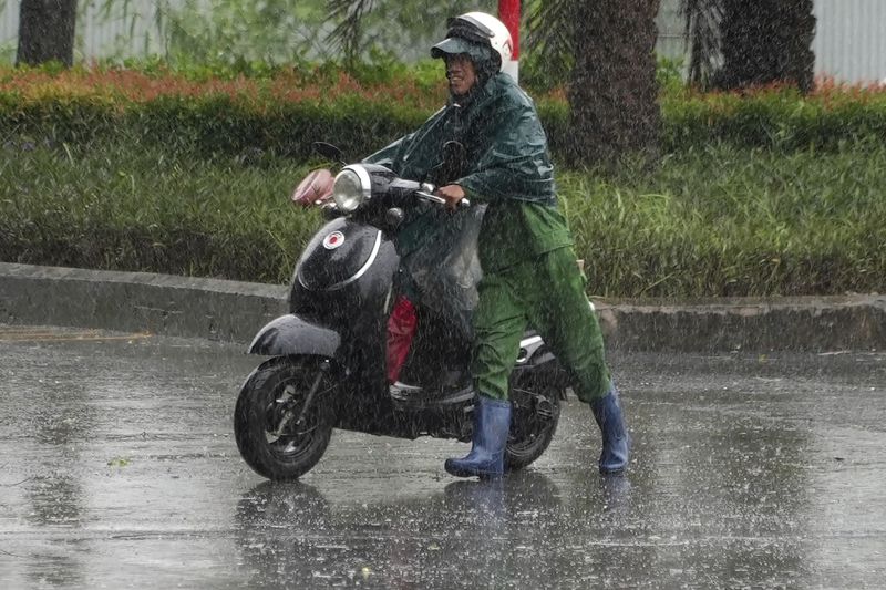 A man pushes a motorcycle in the rain caused by typhoon Yagi in Hanoi, Vietnam Saturday, Sep. 7, 2024. (AP Photo/Hau Dinh)