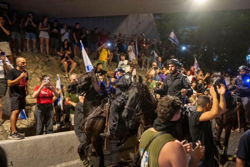 People protest, calling for a deal for the immediate release of hostages held in the Gaza Strip by Hamas, as law enforcement on horses respond in Tel Aviv, Israel, Sunday, Sept. 1, 2024. (AP Photo/Ohad Zwigenberg)