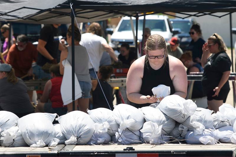Volunteer Teri Moreland ties the top of a sandbag while helping fill sandbags at the Jefferson Community Center in Jefferson, South Dakota, Sunday, June 23, 2024. The sandbagging is an attempt to save homes and keep floodwaters from the Big Sioux River from inundating the town. (Tim Hynds/Sioux City Journal via AP)