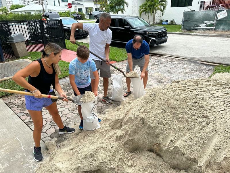 Residents in the sea-side town of Surfside, Fla., fill sandbags to protect their homes for more flooding expected on Thursday, June 13, 2024. A tropical disturbance brought a rare flash flood emergency to much of southern Florida the day before. Floridians prepared to weather more heavy rainfall on Thursday and Friday. (AP Photo/Wilfredo Lee)