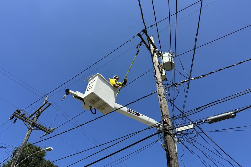 Robert Cowboy Geiser, 39, fixes a power line after widespread electrical outages from Hurricane Francine Friday, Sept. 13, 2024, in New Orleans, La. (AP Photo/Jack Brook)