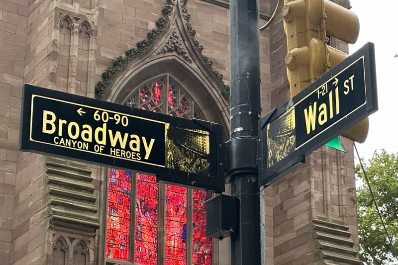 FILE - Signs mark the intersection of Broadway and Wall Street in the Financial District on Oct. 2, 2024, in New York. Trinity Church is in the background. (AP Photo/Peter Morgan, File)