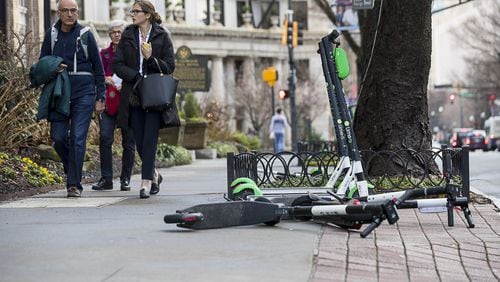 Pedestrians walk past Lime and Bird scooters that are parked on the sidewalk of Peachtree Street in Atlanta’s Midtown community, Friday, January 4, 2019. (ALYSSA POINTER/ALYSSA.POINTER@AJC.COM)