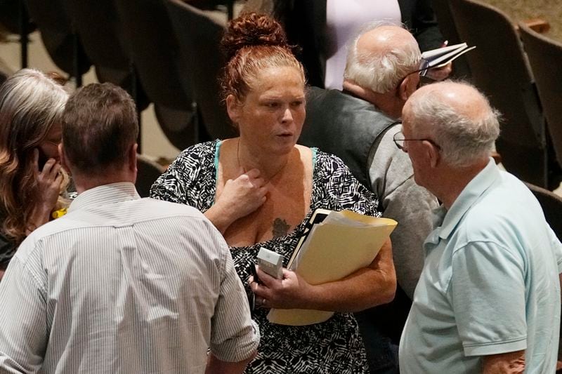 Jami Wallace, center, talks with other audience members during a break in a meeting of the National Transportation Safety Board to discuss and the Norfolk Southern Train Derailment Investigation Tuesday, June 25, 2024, in East Palestine, Ohio. (AP Photo/Sue Ogrocki)