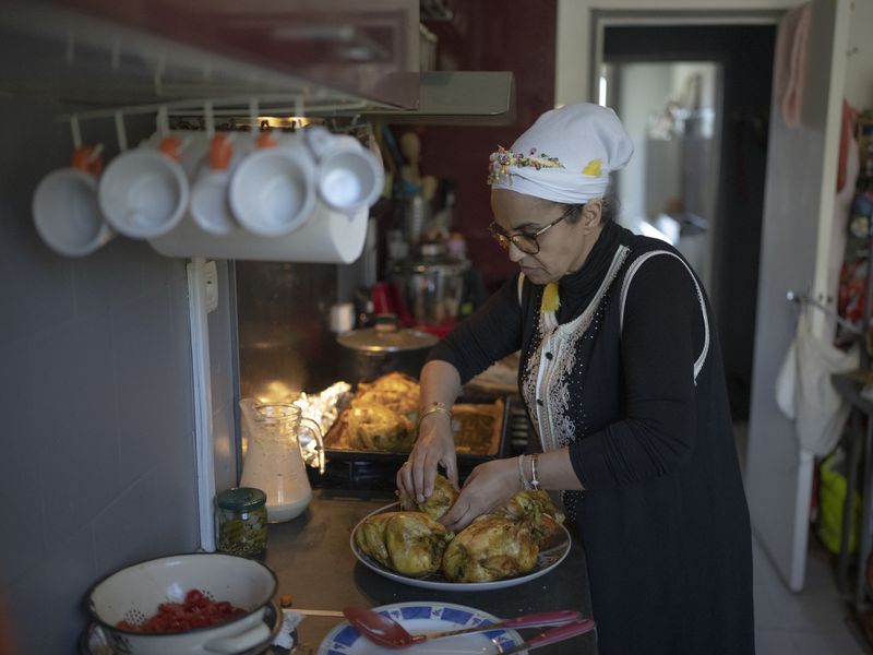 Majda Ould Ibbat prepares a traditional Morroccan chicken dish at home in Marseille, southern France, Sunday, April 21, 2024. (AP Photo/Daniel Cole)