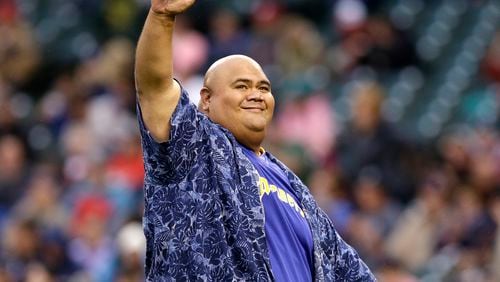 FILE - Actor Taylor Wily, also known as Teila Tuli, of "Hawaii Five-0," gestures to fans after throwing out the ceremonial first pitch before a baseball game between the Seattle Mariners and Texas Rangers in Seattle on June 14, 2014. (AP Photo/Elaine Thompson, File)