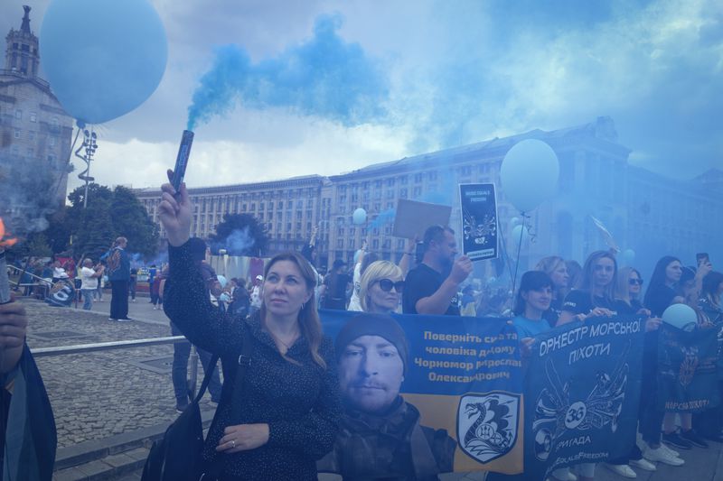 Relatives and activists light flares and hold portraits of POWs during a rally demanding the release of Ukrainian soldiers who were captured by Russia during the war, in the Independence square in Kyiv, Ukraine, Thursday, May 23, 2024. (AP Photo/Efrem Lukatsky)