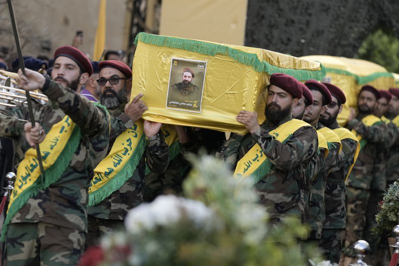 Hezbollah fighters carry the coffins of their comrades who were killed in Friday's Israeli strike, during their funeral procession in the southern suburb of Beirut, Saturday, Sept. 21, 2024. (AP Photo/Bilal Hussein)