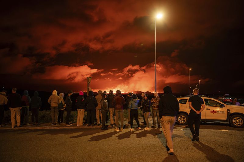 Tourists and visitors try to get a view of the eruption from a distance from the intersection between Reykjanesbraut, Iceland, and the road to Grindavik, Thursday, Aug. 22, 2024. (AP Photo/Marco di Marco)