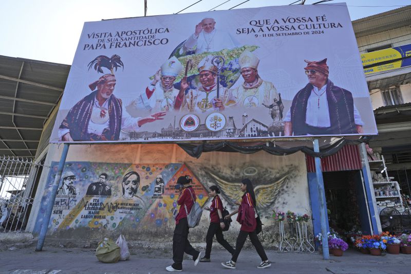 A billboard welcoming Pope Francis stands above a mural honoring Bishop Belo and three others as national heros in Dili, East Timor, Wednesday, Aug. 14, 2024. (AP Photo/Achmad Ibrahim)