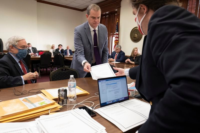 FILE -- Georgia Republican Shawn Still, who became a state senator in 2022 and is seeking reelection in 2024, hands an electoral certificate to Donald Trump campaign worker Robert Sinners during a meeting of Republican electors who cast votes for Trump and Vice President Mike Pence at the Georgia Capitol, Dec. 14, 2020, in Atlanta. (AP Photo/Ben Gray, File)