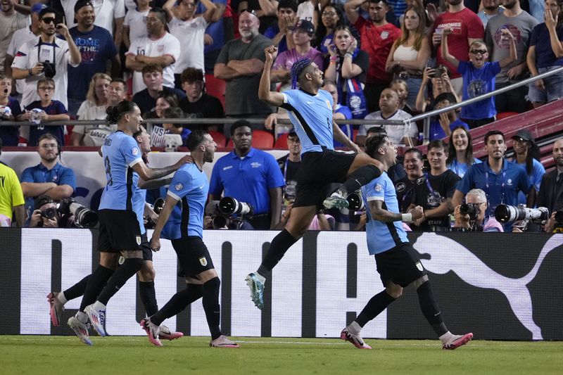 Uruguay's Ronald Araujo, second from right, leaps as he celebrates a goal by Mathias Olivera, right, during a Copa America Group C soccer match against the United States, Monday, July 1, 2024, in Kansas City, Mo. (AP Photo/Ed Zurga)