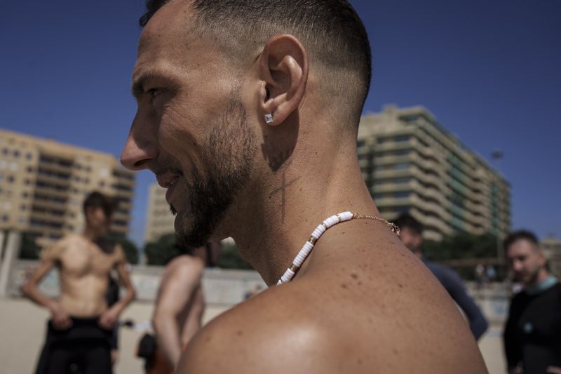 Rochat Ludovic talks to members of Surf Church before they catch waves in Matosinhos beach in the suburbs of Porto, Portugal on Sunday, Aug. 18, 2024. (AP Photo/Luis Andres Henao)