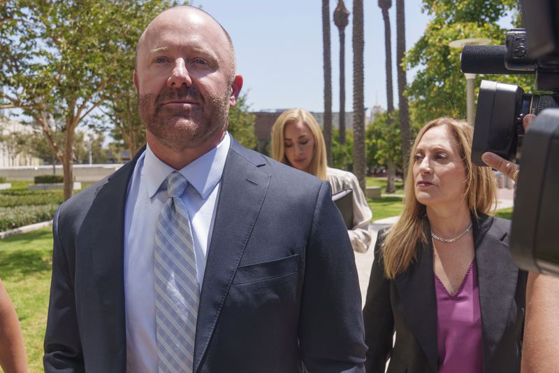 Mathew Bowyer, left, a Southern California bookbinder, arrives with his attorney, Diane Bass, right, in federal court in Santa Ana, Calif., Friday, Aug. 9, 2024. (AP Photo/Damian Dovarganes)