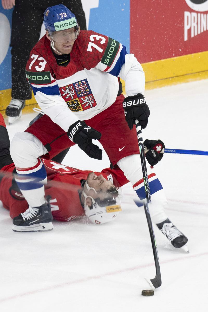 Switzerland's Dean Kukan, bottom, lies on the ic behind Czech Republic's Ondrej Kase (73) during the Ice Hockey World Championship final match in Prague, Czech Republic, at the O2 Arena, Sunday, May 26, 2024. (Peter Schneider/Keystone via AP)