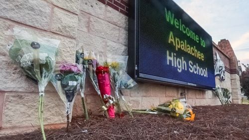 Flowers are placed at the foot of the welcome sign to Apalachee High School for a makeshift memorial on Sept. 5, the day after a shooting killed four people. (John Spink/AJC)