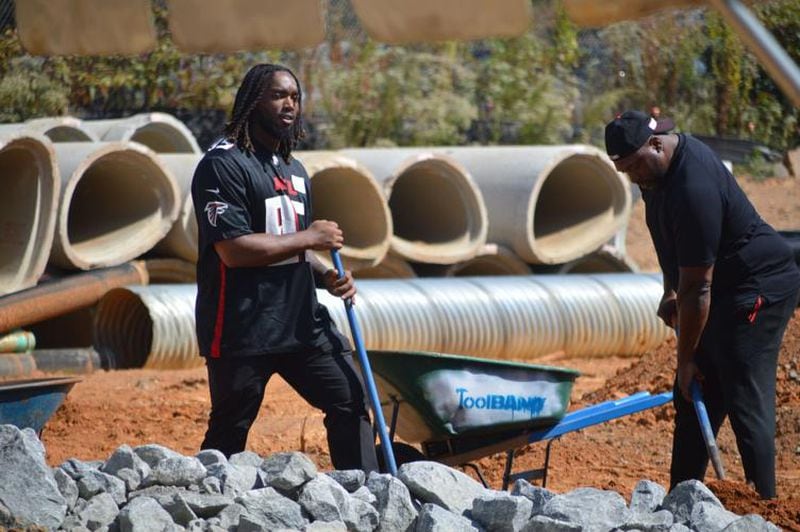 Atlanta Falcons defensive lineman Ta’Quon Graham, left, shovels dirt at the PlayTown Suwanee site on Tuesday. Members of the Falcons organization helped PlayTown Suwanee officials build some of the playground at the Suwanee Town Center on Main site. (Photo Courtesy of Curt Yeomans)