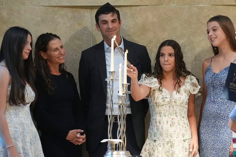 Quinn Schimel, second from left, lights a Shabbat candle as she stands with her family during a Shabbat service, Friday, Sept. 27, 2024, at Temple Beth Sholom in Miami Beach, Fla. (AP Photo/Wilfredo Lee)