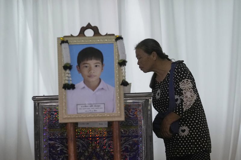 A relative looks at the coffin of a victim of school bus fire at Wat Khao Phraya Sangkharam School Lan Sak, Uthai Thani province, Thailand, Thursday, Oct. 3, 2024. (AP Photo/Sakchai Lalit)