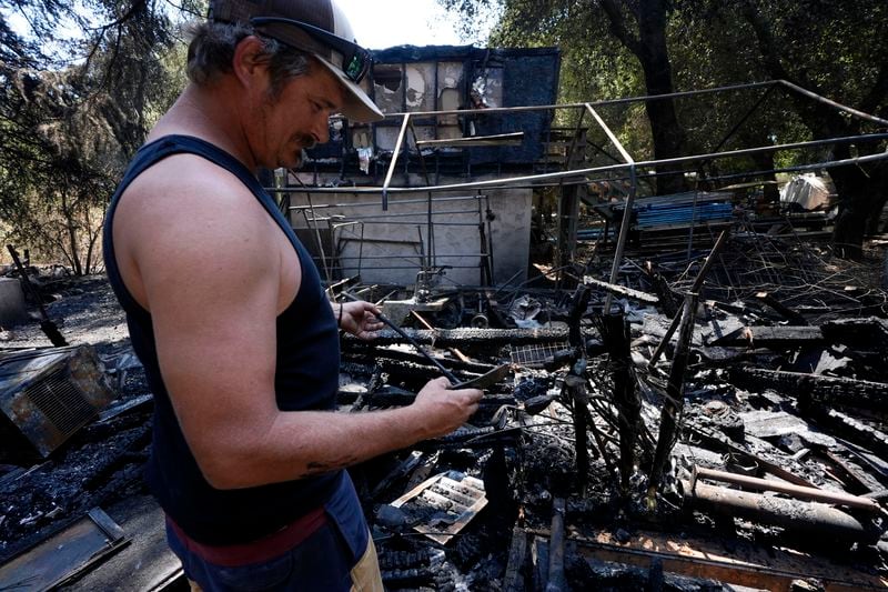 Matt Howe sifts through his partially damaged property after the Airport Fire swept through Thursday, Sept. 12, 2024, in El Cariso Village, in unincorporated Riverside County, Calif. (AP Photo/Gregory Bull)