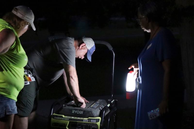 Joe Hackl, center, and Terri Hackl, left, deliver a generator to an independent living center where several dozen seniors lost power in the wake of Hurricane Beryl in Houston on Thursday, July 11, 2024. Like-minded community efforts have brought relief in the form of fresh food and cool air for some of the millions who sweltered this week without electricity. (AP Photo/James Pollard)