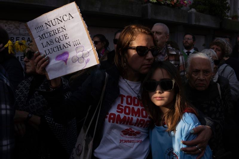 A woman holds a sign that reads in Spanish; "Those who fight never die," during the burial service of Amelia Sanjurjo at La Teja cemetery in Montevideo, Uruguay, Thursday, June 6, 2024. The Uruguayan Prosecutor’s Office confirmed that the human remains found in June 2023 at the 14th Battalion of the Uruguayan Army belong to Sanjurjo, a victim of the 1973-1985 dictatorship who was 41 years old and pregnant at the time of her disappearance. (AP Photo/Matilde Campodonico)