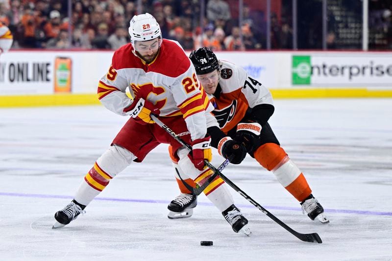 FILE - Calgary Flames' Dillon Dube, left, skates the puck past Philadelphia Flyers' Owen Tippett, right, during the third period of an NHL hockey game Jan. 6, 2024, in Philadelphia. Four current members of the National Hockey League charged with sexual assault in Canada will become free agents after not receiving qualifying offers from their respective teams. Carter Hart was under contract with Philadelphia, Michael McLeod and Cal Foote with New Jersey and Dube with Calgary when they were charged in connection with an incident that occurred in London, Ontario, in 2018 after they were teammates on Canada's world junior team. (AP Photo/Derik Hamilton, File)