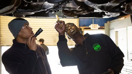 Student, Brandon Oates (left) and instructor Larry Witherspoon Jr. inspect a vehicle on a lift at the Automotive Training Center in East Point. Photo by Phil Skinner