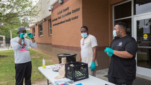 Working to distribute food at DeKalb County’s Exchange Park Recreation Center, William Smith, the center’s director ( left) Nicholas Dixon, a counselor at the center, and assistant director Leonard Allen provide fresh fruit, juice and cookies as well as coloring books and crayons for public school students Wednesday, April 8, 2020. Jenni Girtman for The Atlanta Journal-Constitution