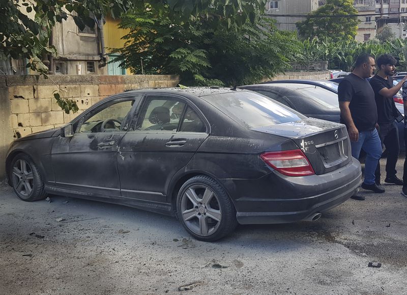 Lebanese security officers stand next of a partly damaged car after what is believed to be the result of a walkie-talkie exploding inside it, in the southern port city of Sidon, Lebanon, Wednesday, Sept. 18, 2024. (AP Photo/Mohammed Zaatari)