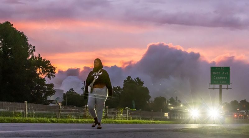 As Lauryn Daniels walks, a white cloud of chemical smoke extends across the sky. Rockdale County residents were told to shelter in place again on Tuesday.