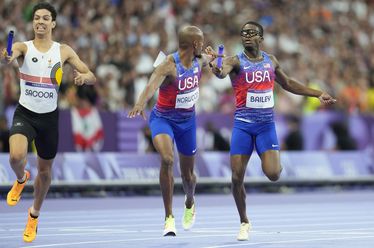 Christopher Bailey, of the United States, hands the baton to teammate Vernon Norwood, in the men's 4 x 400 meters relay final at the 2024 Summer Olympics, Saturday, Aug. 10, 2024, in Saint-Denis, France. (AP Photo/Ashley Landis)