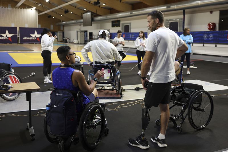 Wheelchair fencer Jataya Taylor from the U.S., left, and U.S. Paralympic snowboarder Mike Schultz talk during a wheelchair fencing practice at the U.S. team High Performance Center during the Paralympic Games in Paris on Wednesday, Aug. 28, 2024. (AP Photo/Avni Trivedi)