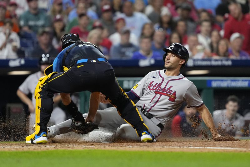 Atlanta Braves' Matt Olson, right, is taggeed out by Philadelphia Phillies catcher J.T. Realmuto after trying to score on a wild pitch by Yunior Marte during the seventh inning of a baseball game, Friday, Aug. 30, 2024, in Philadelphia. (AP Photo/Matt Slocum)