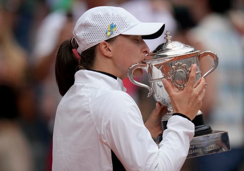 FILE - Poland's Iga Swiatek kisses the trophy as she celebrates winning the women's final match of the French Open tennis tournament against Karolina Muchova of the Czech Republic in three sets, 6-2, 5-7, 6-4, at the Roland Garros stadium in Paris, Saturday, June 10, 2023. Swiatek has been No. 1 in the WTA rankings for most of the past two years and will seek her fourth championship at Roland Garros — and fifth Grand Slam trophy overall — when play begins at the clay-court major tournament Sunday. (AP Photo/Christophe Ena, File)