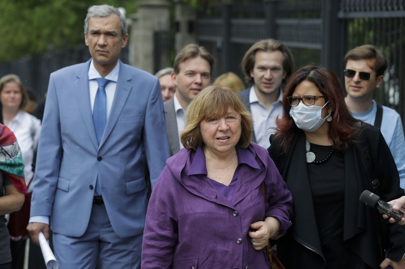 FILE - Svetlana Alexievich, the 2015 Nobel literature laureate, center, and Pavel Latushko, former culture minister and ambassador to France, left, walk amid supporters and journalists on their way to the office of the Belarusian Investigative Committee in Minsk, Belarus, on Aug. 26, 2020. (AP Photo, File)