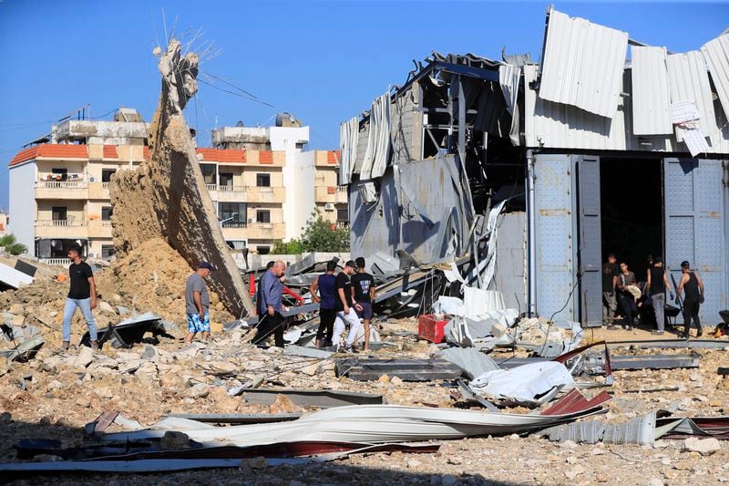 People gather at the site of an Israeli airstrike that hit a hangar in the southern town of Jiyeh, Lebanon, Wednesday, Sept. 25, 2024. (AP Photo/Mohammed Zaatari)