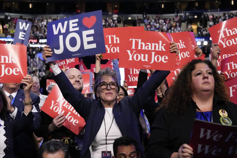 Delegates hold signs as President Joe Biden speaks during the first day of Democratic National Convention, Monday, Aug. 19, 2024, in Chicago. (AP Photo/Jacquelyn Martin)