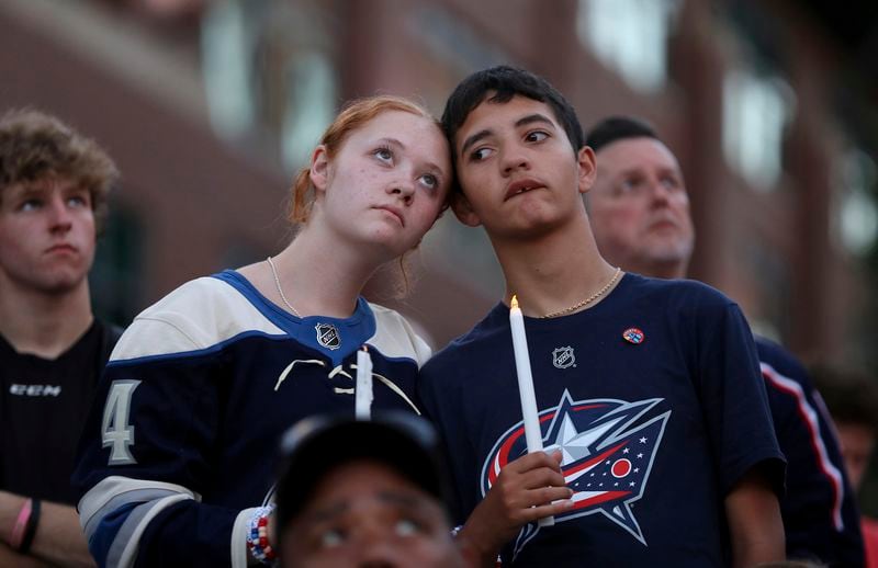 Blue Jackets fans Gianna,left, and Elijah Willis, have a moment of silence during the candlelight vigil to honor Columbus Blue Jackets hockey player Johnny Gaudreau, outside of Nationwide Arena in Columbus, Ohio, Thursday, Sept. 4, 2024. Gaudreau and his brother Matthew were killed by a motor vehicle last week while riding bicycles. (AP Photo/Joe Maiorana)