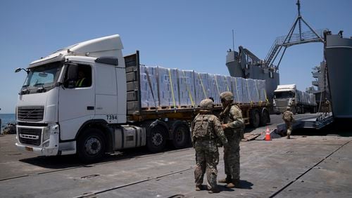 FILE - U.S. Army soldiers stand next to trucks arriving loaded with humanitarian aid at the U.S.-built floating pier Trident before reaching the beach on the coast of the Gaza Strip, June 25, 2024. (AP Photo/Leo Correa, File)