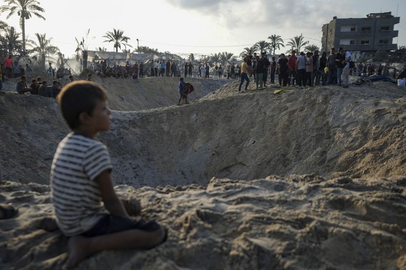 Palestinians look at the destruction after an Israeli airstrike on a crowded tent camp housing Palestinians displaced by the war in Muwasi, Gaza Strip, Tuesday, Sept. 10, 2024. An Israeli strike killed at least 40 people and wounded 60 others early Tuesday, Palestinian officials said. Israel said it targeted "significant" Hamas militants, allegations denied by the militant group. (AP Photo/Abdel Kareem Hana)