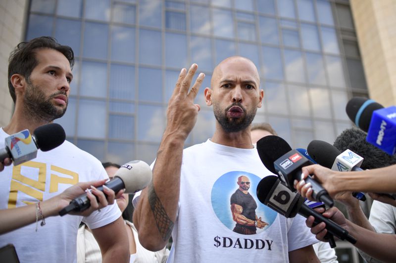 Andrew Tate speaks to media outside the Bucharest Tribunal after being placed under house arrest, in Bucharest, Romania, Thursday, Aug. 22, 2024. A court in Romania's capital on Thursday placed the divisive internet influencer Andrew Tate under house arrest for 30 days, as prosecutors investigate a sprawling new case that involves allegations of human trafficking of minors and sex with a minor. (AP Photo/Alexandru Dobre)