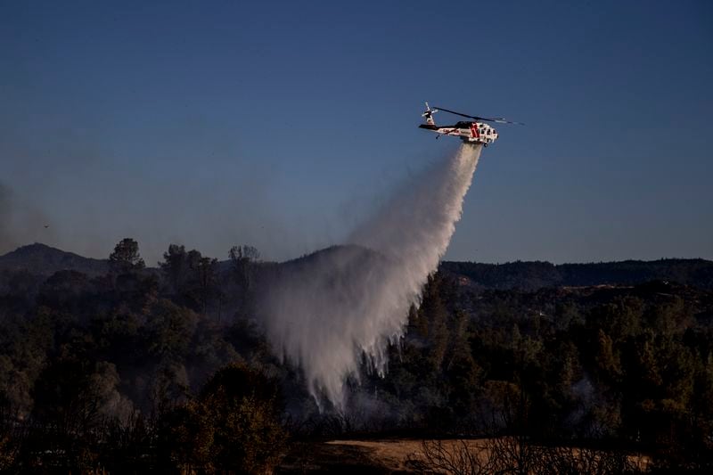 A Cal Fire Sikorsky S70i Firehawk helicopter performs a water drop on a hot spot during the Boyles fire in Clearlake, Calif., Sunday, Sept. 8, 2024. (Stephen Lam/San Francisco Chronicle via AP)