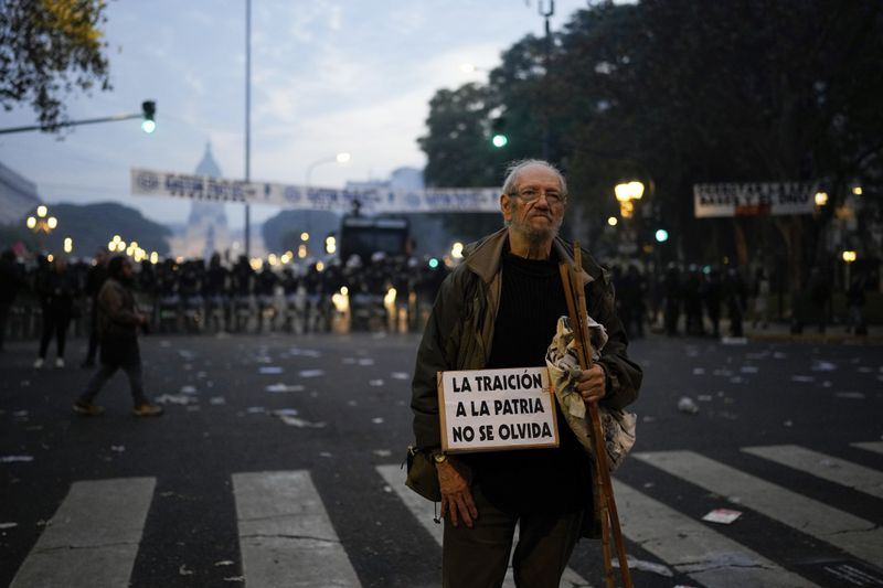 An anti-government protester stands in front of police outside Congress, where lawmakers debate a reform bill promoted by Argentine President Javier Milei in Buenos Aires, Argentina, Wednesday, June 12, 2024. (AP Photo/Natacha Pisarenko)