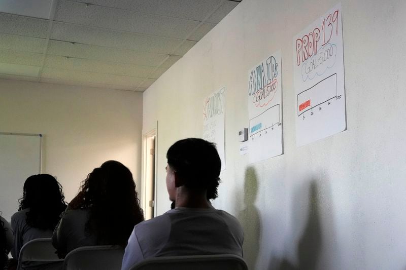 Poder In Action canvassers listen to a lecture on their mission prior to a neighborhood canvassing voter outreach event Tuesday, Sept. 3, 2024, in Phoenix. (AP Photo/Ross D. Franklin)