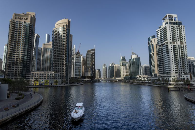 People sit on a boat as it sails along Dubai Marina, United Arab Emirates, Tuesday, Aug. 13, 2024. (AP Photo/Altaf Qadri)