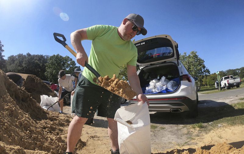 Justin Fogle, of College Parks, fills a sandbag at the Orange County distribution site at Barnett Park in Orlando, Fla., Tuesday, Sept. 24, 2024, ahead of the forecast for the possibility of heavy rains in Central Florida. (Joe Burbank/Orlando Sentinel via AP)