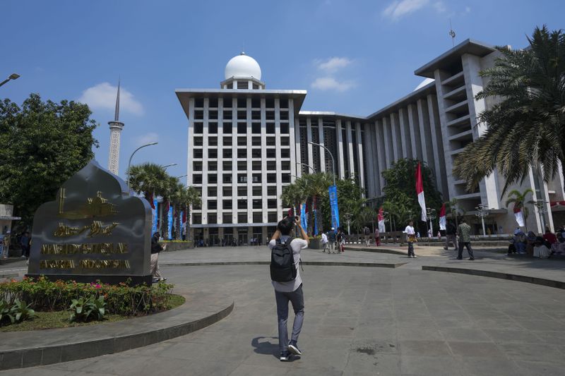 A man uses his mobile phone to take photos outside Istiqlal Mosque in Jakarta, Indonesia, Friday, Aug. 9, 2024, where Pope Francis is scheduled to hold an interfaith meeting on Sept. 5. (AP Photo/Tatan Syuflana)